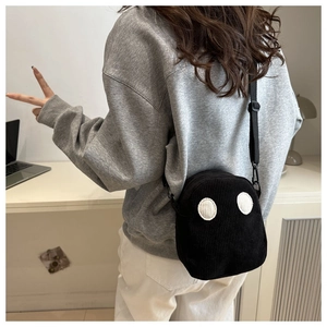 Détail du sac à bandoulière en velours côtelé noir avec yeux de dessin animé porté