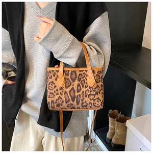 Dettaglio di una piccola borsa a secchiello leopardata con manici color caramello sulla modella