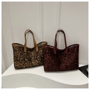 Detail of leopard print tote bags in yellow-brown and burgundy with leather handles