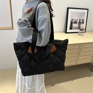 Quilted tote bag with floral accents and wide shoulder strap for everyday commuting