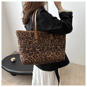 Detail of leopard print tote bag featuring brown leather shoulder straps and spacious interior