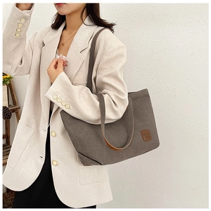 Sac fourre-tout en toile grise avec poignées en cuir marron porté par un mannequin