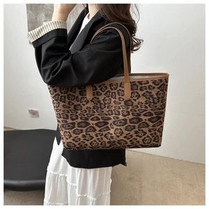 Fashionable leopard print tote bag with brown leather handles worn by a stylish model