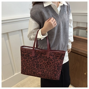 Detail of large leopard print tote bag with brown leather handles on shoulder