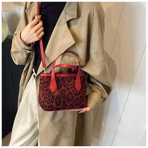Dettaglio della borsa a secchiello leopardata con finiture in pelle rossa e tracolla