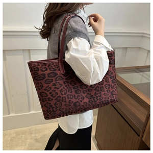 Detail of burgundy leopard print tote bag with slim shoulder straps worn by a model