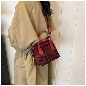 Borsa a secchiello leopardata alla moda con cinturini rossi indossata su un cappotto
