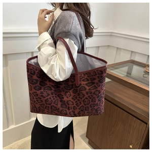Detail view of large leopard print tote bag on shoulder showing red and black pattern