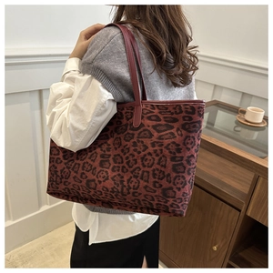 Fashionable leopard print tote bag with red leather handles shown in a lifestyle scene