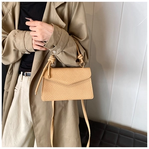 Dettaglio della trama intrecciata beige e del manico annodato della borsa a tracolla