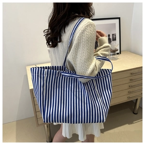 Vue détaillée du grand sac cabas en toile à rayures bleues et blanches porté à l'épaule