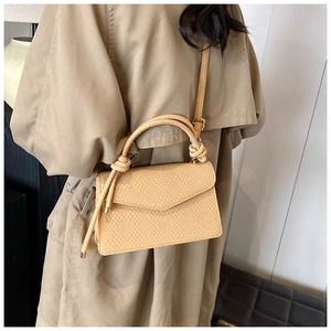 Détail du sac beige tissé avec poignée tressée épaisse et bandoulière réglable