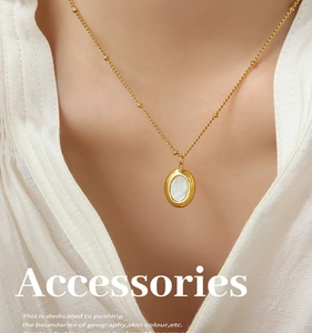 Primer plano de collar de titanio dorado con colgante ovalado de nácar en una modelo
