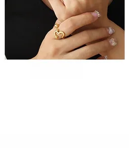 Vue macro d'une bague ouverte torsadée plaquée or portée sur un doigt avec nail art
