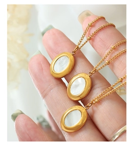 Detalle macro de colgantes ovalados de nácar en collares de acero de titanio dorado