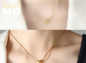 Détail du collier chaîne serpent dorée avec pendentif gland perle sur le cou
