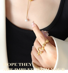 Gros plan d'un collier chaîne serpent doré avec perle et une bague courbée ondulée