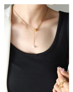Gros plan d'un collier en Y doré avec un élégant pendentif en perle blanche détaillée