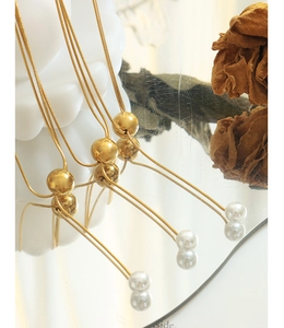 Vue détaillée d'un collier chaîne serpent dorée avec perle coulissante et pendentifs