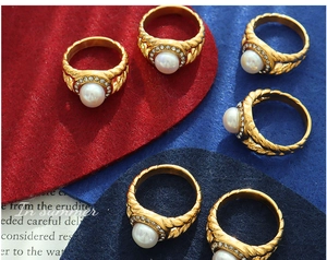 Macro detail of gold-plated braided ring featuring a freshwater pearl and zircon halo