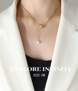 Détail du collier à chaîne serpent dorée avec pendentif en perle sur une veste de mannequin