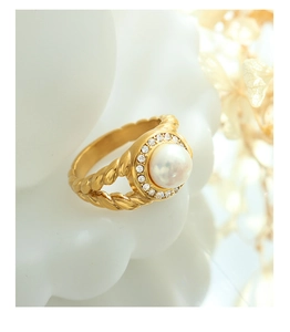 Detail of twisted gold ring band featuring a white pearl and zircon halo setting