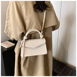 Modern white knit square handbag worn cross-body style by a model in a minimal setting
