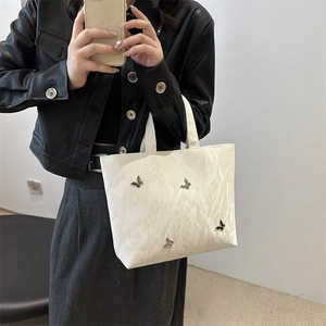 White pleated tote bag with silver butterfly charms shown in a stylish commute outfit