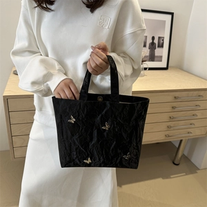 Large black textured tote bag with silver butterfly charms for stylish commuting