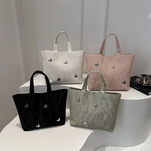 Silver butterfly textured tote bags in white pink black and sage green set on white steps