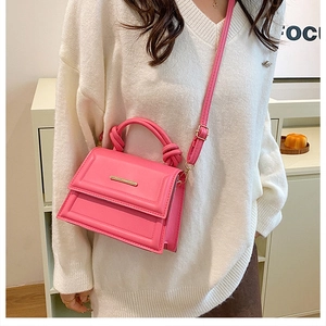 Modern rose pink leather crossbody bag with a unique knot handle and gold hardware