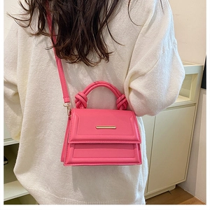 Detail of pink crossbody bag with a knotted top handle and gold metal trim decoration