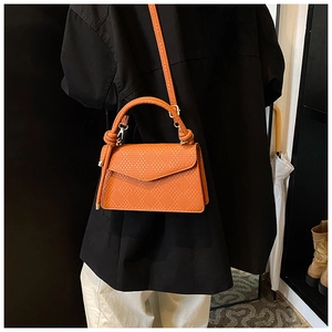 Detail of orange woven crossbody bag with envelope flap and circular top handle
