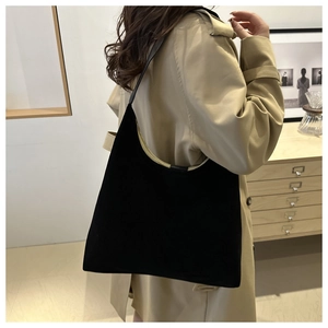 Detail of the black suede crescent shoulder bag showing its capacity and minimalist design