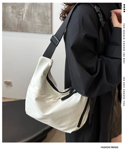 Detailed shot of white crescent tote with black adjustable strap and pleated fabric texture