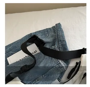 Detail of adjustable black nylon strap with plastic buckle on a white crossbody bag
