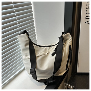 Detail of off-white nylon crossbody crescent bag with adjustable black strap and buckle