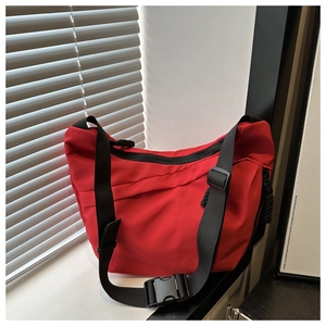Detail of red large capacity tote bag with black adjustable strap and buckle closure