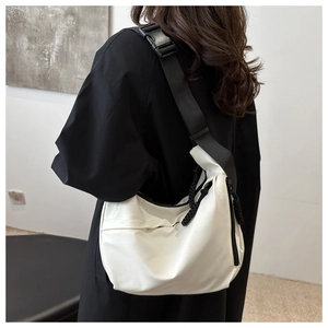 Detail of the off-white nylon dumpling bag with adjustable wide black shoulder strap