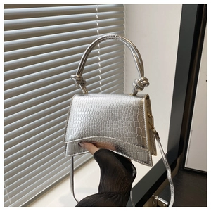 Detail of silver crocodile pattern bag with metallic finish and knotted handle detail