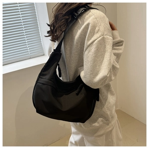 Detailed back view of a black crescent nylon crossbody bag on a model in a minimalist setting