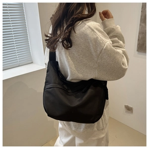 Side view of a black large-capacity nylon crossbody bag worn by a model for daily use