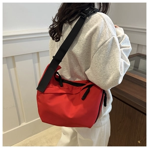 Detail of red nylon tote bag featuring adjustable black wide strap and durable buckle