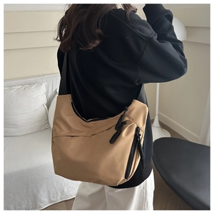 Detail of khaki nylon crescent bag with black zipper detail worn by a model