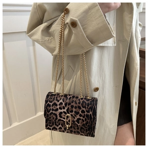 Detail of leopard print crossbody bag with gold chain and metal clasp on beige trench coat