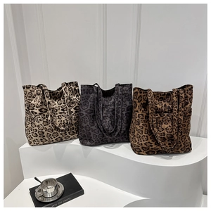 Tre borse tote in camoscio con stampa leopardata in vari colori su piattaforma bianca