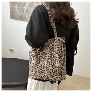Vista laterale della borsa tote in tela con stampa leopardata e tracolla in una stanza