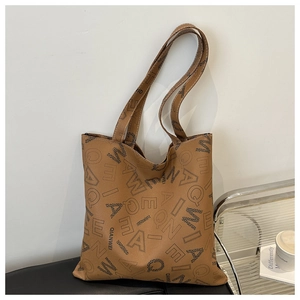 Detail of a brown PU tote bag with QIANWEI letter print on a black bench