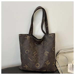 Close-up of textured dark brown leather tote bag with yellow letter monogram pattern