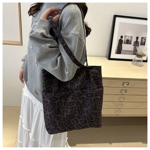 Borsa tote grande con stampa leopardata viola portata a spalla in un ambiente minimalista